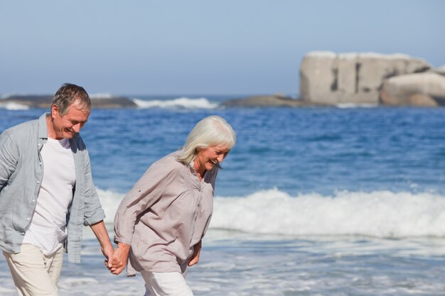 Couple de personnes âgées marchant sur la plage