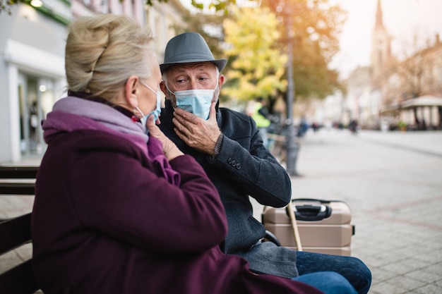 Couple de personnes âgées en masque de protection à l'extérieur de la ville. Notion de pollution atmosphérique.