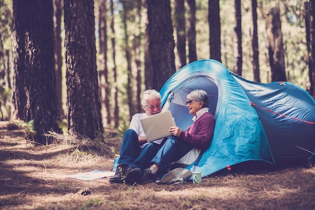 Couple de personnes âgées matures profitant de la nature des activités de loisirs en plein air assis à l'extérieur d'une tente dans la forêt Heureux jeune homme et femme vieillesse senior mode de vie en camping gratuit et voyage alternatif