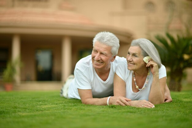 Couple de personnes âgées posant sur l'herbe au resort