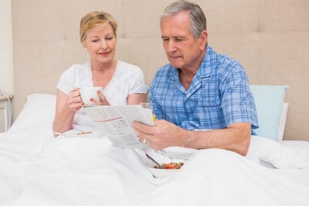 Couple de personnes âgées prenant son petit déjeuner au lit