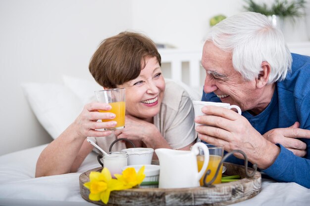 Couple de personnes âgées prenant son petit déjeuner au lit