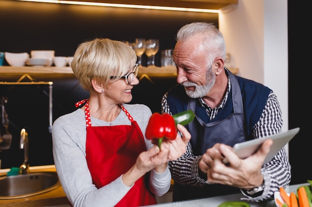 Couple de personnes âgées préparant le déjeuner ensemble dans la cuisine.