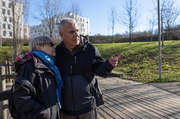 Photo couple de personnes âgées à la recherche d'un endroit où l'homme pointe dans la bonne direction avec son doigt