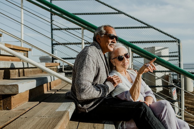 Couple de personnes âgées romantique assis sur la jetée