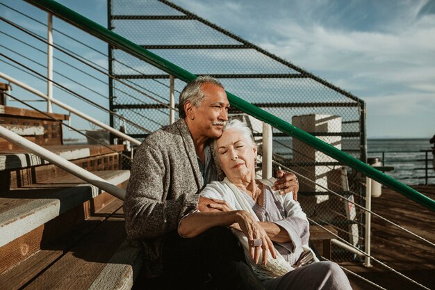 Couple de personnes âgées romantique assis sur la jetée