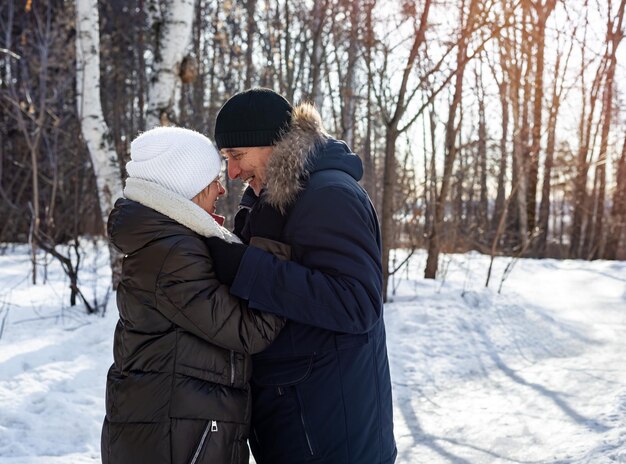 Couple de personnes âgées s'embrassant à la campagne au coucher du soleil dans la forêt d'hiver relation familiale Style de vie