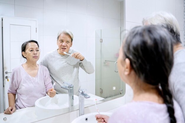 Couple de personnes âgées se brosser les dents dans la salle de bain