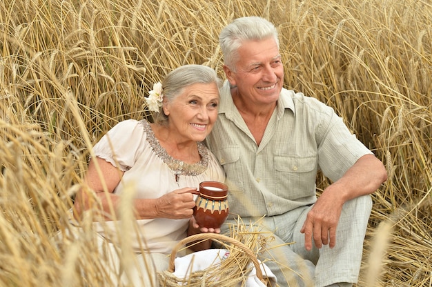 Couple de personnes âgées se reposant au champ d'été avec du lait dans une cruche