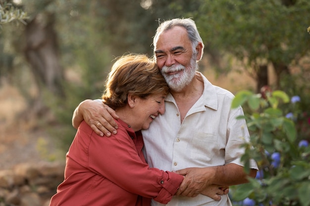 Couple de personnes âgées se tenant romantiquement dans leur jardin de campagne