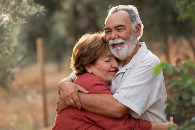 Couple de personnes âgées se tenant romantiquement dans leur jardin de campagne