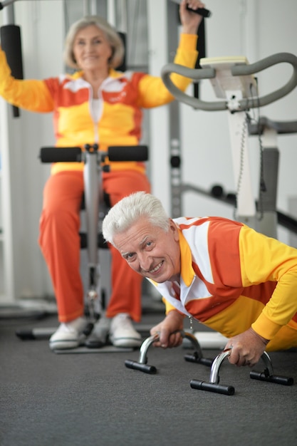 Photo couple de personnes âgées souriant actif exerçant dans une salle de sport