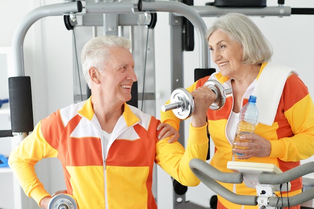Couple de personnes âgées souriant actif exerçant dans une salle de sport