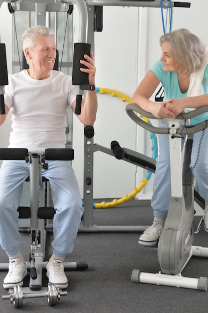 Couple de personnes âgées souriant actif faisant de l'exercice dans une salle de sport