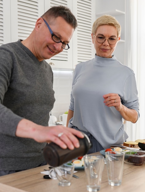 Un couple de personnes âgées sportif en bonne santé prend des protéines de complément alimentaire du shaker avant le dîner actif