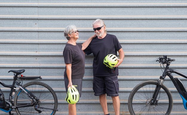 Photo un couple de personnes âgées tenant un casque de vélo contre le mur