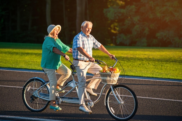 Photo couple de personnes âgées sur vélo tandem