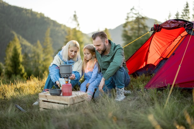 Couple avec petite fille pique-nique au camping dans les montagnes