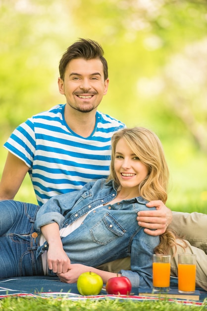 Un couple pique-nique dans un parc et boit du jus.