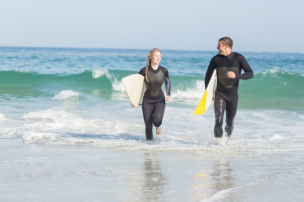 Couple avec planche de surf sur la plage