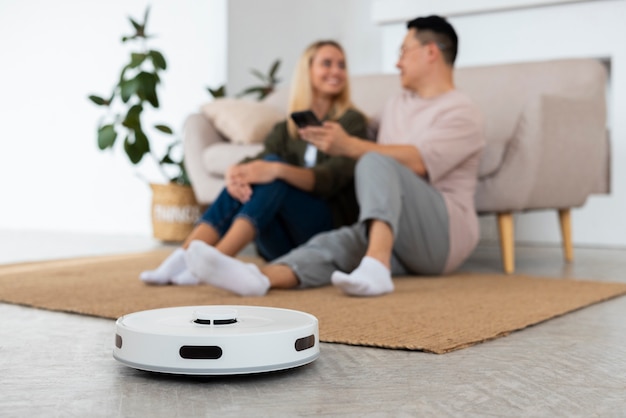 Photo couple plein coup avec aspirateur robotique à la maison