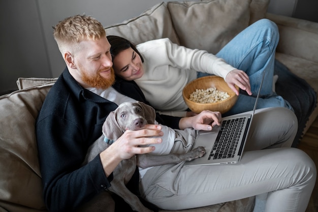 Photo couple plein coup et chien regardant un film