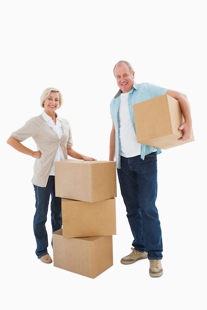 Couple plus âgé, souriant à la caméra avec des boîtes de déménagement