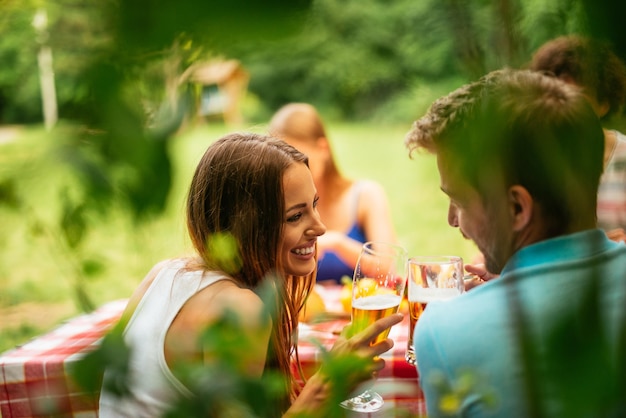 Couple portant un toast avec de la bière lors d'un pique-nique