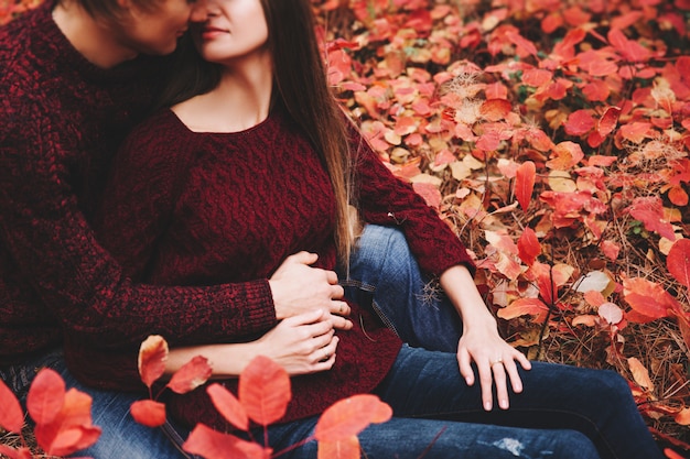 Couple porté dans des vêtements de style automne, la famille des pulls ressemble à travers le paysage d'automne. Forêt couverte de feuillage jaune. Promenade d'automne à l'extérieur.