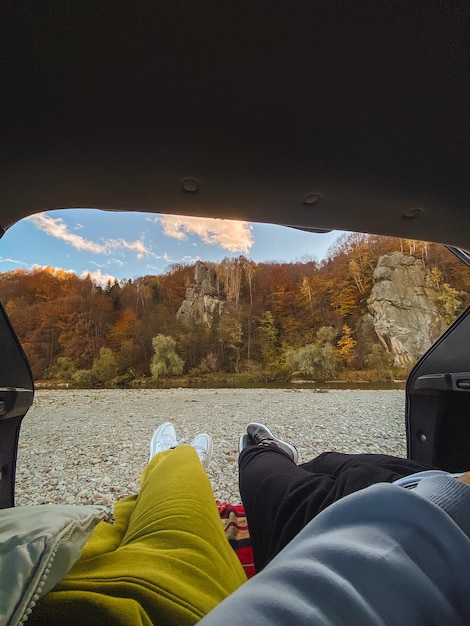 Photo couple de pov allongé dans le coffre de la voiture avec vue sur la rivière de la montagne d'automne