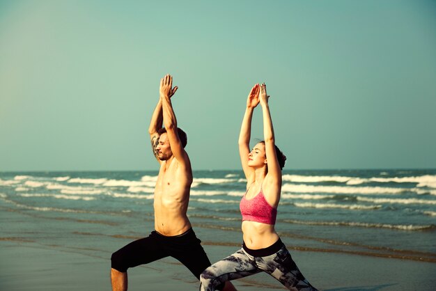 Couple pratiquant le yoga à la plage