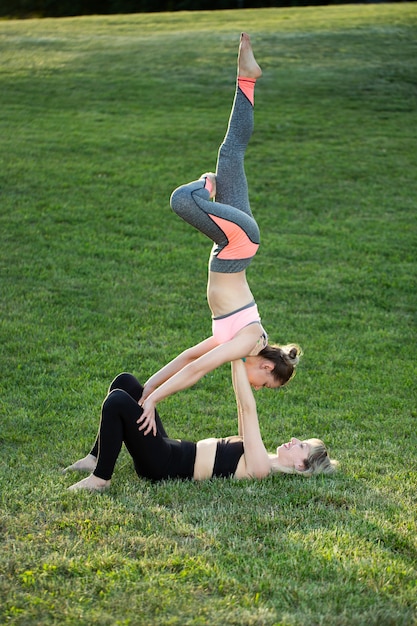 Le couple pratique l'acro yoga dans le parc sur l'herbe