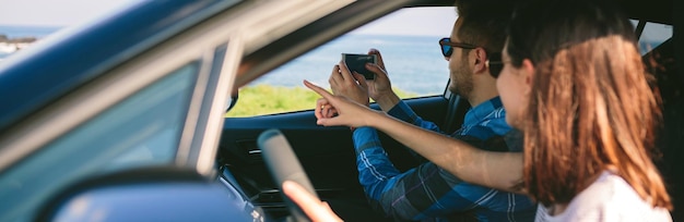 Photo couple prenant une photo de paysage depuis la voiture