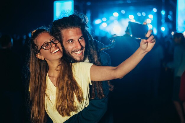 Couple prenant un selfie avec un smartphone lors d'un festival de musique