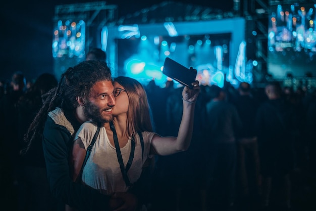 Couple prenant un selfie avec un smartphone lors d'un festival de musique