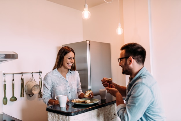 Couple prenant son petit déjeuner au comptoir de la cuisine.