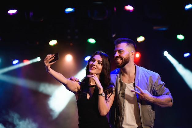 Couple prend un selfie avec un téléphone portable lors de la fête de nuit