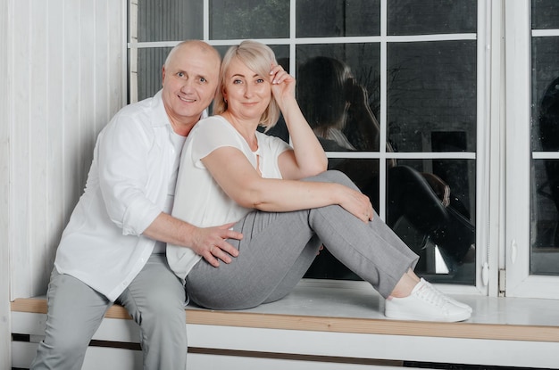 couple près de la fenêtre étreignant, embrassant et souriant