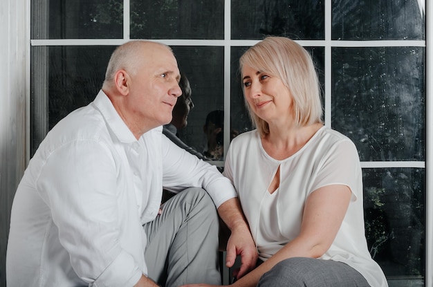 couple près de la fenêtre étreignant, embrassant et souriant