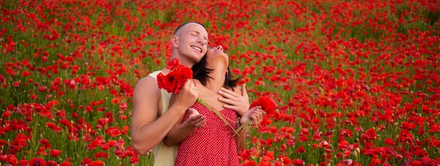 Couple de printemps amoureux bannière couple heureux respirant de l'air frais dans un champ de pavot ou une pelouse de fleurs