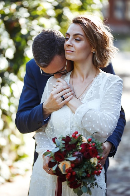 Photo couple profitant de moments romantiques en se promenant dans le parc mariée et le marié élégants posant et s'embrassant