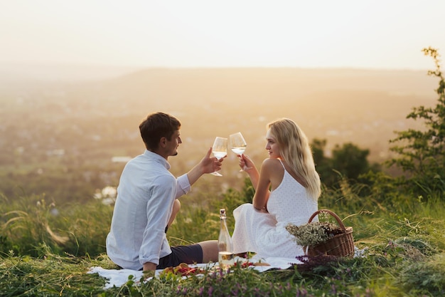 couple profitant de verres à vin et d'une journée de pique-nique sur la colline