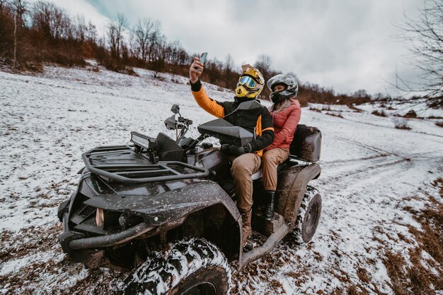 un couple profite d'une aventure en quad à travers le paysage enneigé capturant le frisson de la