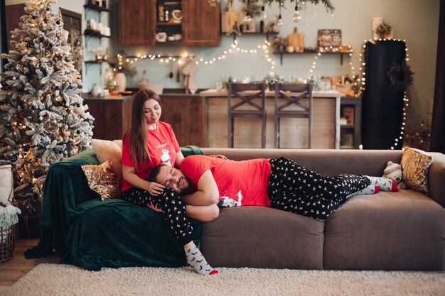 Couple en pyjama de Noël similaire assis sur un canapé