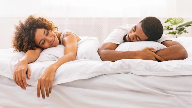 Un couple qui dort dos à dos dans le lit.