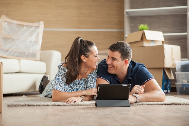 Un couple qui vient d'emménager dans une nouvelle maison achète des meubles en ligne sur une tablette PC