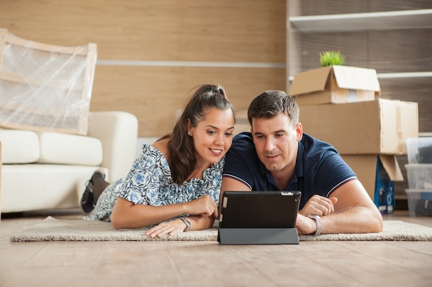 Un couple qui vient d'emménager dans une nouvelle maison achète des meubles en ligne sur une tablette PC