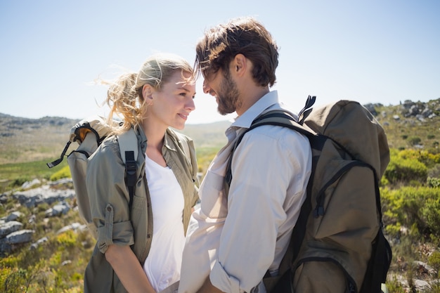 Couple de randonnée debout sur le terrain de montagne en souriant les uns aux autres