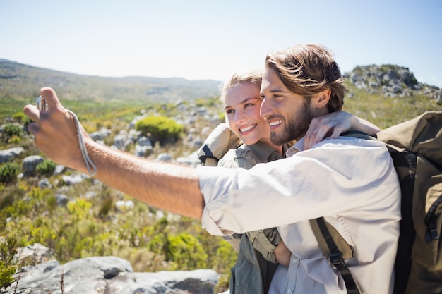 Couple de randonnée debout sur un terrain montagneux prenant un selfie