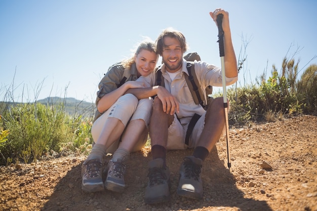 Couple de randonnée prenant une pause sur le terrain de montagne souriant à la caméra